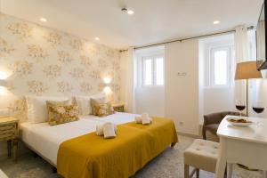 a bedroom with a large bed with a yellow blanket at Suites Amália Guesthouse near Rossio Square in Lisbon