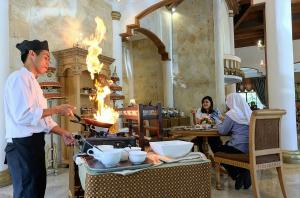 een man die eten kookt op een grill in een restaurant bij Sarasvati Borobudur in Borobudur