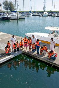 un grupo de personas con chalecos naranjas de pie junto a un barco en el agua en Avillion Admiral Cove, en Port Dickson