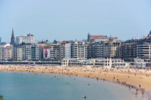 grupa ludzi na plaży przed miastem w obiekcie Hotel Niza w mieście San Sebastián