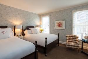 een slaapkamer met 2 bedden en een stoel. bij The Virginia and Cottages in Cape May