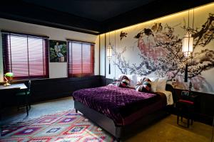 Un dormitorio con una cama morada y una pintura en la pared. en Lao Poet Hotel, en Vientiane