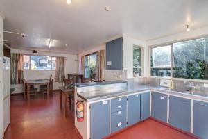 a kitchen with blue cabinets and a dining room with a table at The Flaming Kiwi Backpackers in Queenstown