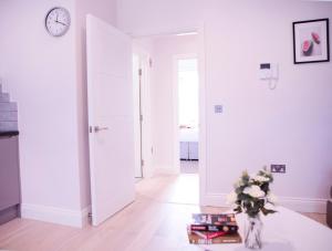 a white room with a vase of flowers on a table at Quiet Central West End Apartments by Indigo Flats in London