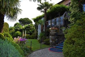 a house with a garden with palm trees and a walkway at Albergo Ristorante Conca Azzurra in Colico