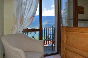 a room with a chair and a balcony with a view at Albergo Ristorante Conca Azzurra in Colico