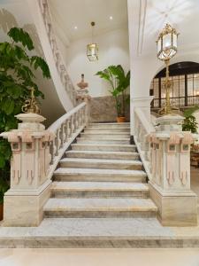 Una escalera en una casa con escaleras de mármol y una lámpara de araña en H10 Palacio Colomera, en Córdoba