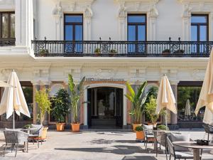 un edificio con mesas, sillas y sombrillas en H10 Palacio Colomera, en Córdoba