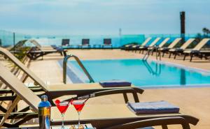 una piscina con sillas y 2 copas de vino en una mesa en Golden Costa Salou - Adults Only 4* Sup, en Salou