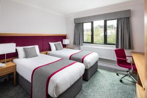 a hotel room with two beds and a desk at Warwick Conferences - Radcliffe in Coventry