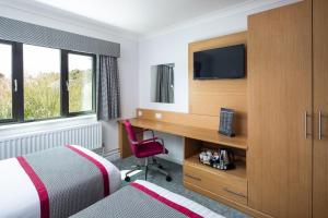 a hotel room with a bed and a desk with a television at Warwick Conferences - Radcliffe in Coventry