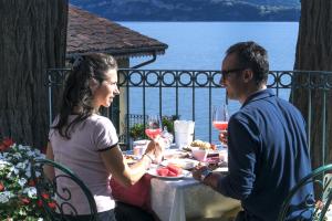 a man and woman sitting at a table with wine glasses at Relais Casali della Cisterna in Belgirate