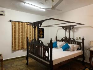 um quarto com uma cama de dossel preta com almofadas azuis em Villa Ameera Malindi em Melinde