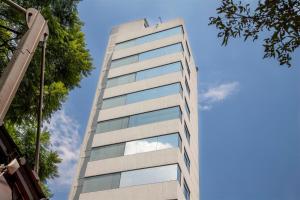 a tall building with glass windows on the side of it at Suites Coben Apartamentos Amueblados in Mexico City