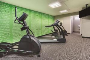 a gym with three cardio machines and a green wall at Days Inn by Wyndham Gainesville Florida in Gainesville