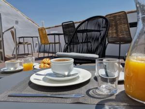 una mesa con una taza de café y un vaso de zumo de naranja en Hotel Boutique Caireles, en Córdoba