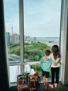 twee kinderen in een kamer die uit een raam kijken bij Hotel X Toronto by Library Hotel Collection in Toronto