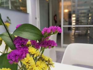 un jarrón lleno de flores moradas y amarillas en una mesa en Hotel Boutique Caireles, en Córdoba