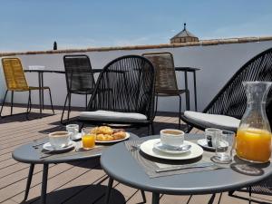 una mesa con comida y zumo de naranja en el balcón en Hotel Boutique Caireles, en Córdoba