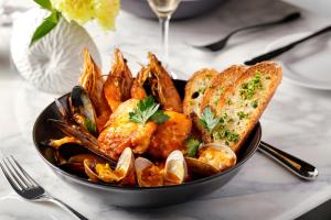 a black bowl of food with shrimp and toast at Halepuna Waikiki by Halekulani in Honolulu