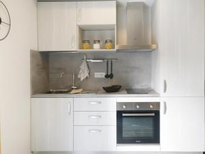 een keuken met witte kasten, een wastafel en een oven bij Domitys Quarto Verde in Bergamo