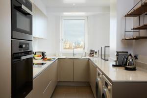 a white kitchen with a large window and a counter at Cheval Gloucester Park at Kensington in London