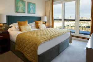 a bedroom with a large bed and a large window at Cheval Gloucester Park at Kensington in London