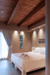 a bedroom with a large white bed with a wooden ceiling at Il Casato Deluxe Rooms in Scilla