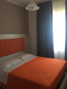 a bedroom with a bed with an orange blanket and a window at Piccolo Hotel Lamezia in SantʼEufemia Lamezia