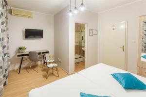 a bedroom with a bed and a desk and a table at Pansion Waldinger in Osijek