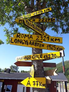 un poteau avec de nombreux signes sur un arbre dans l'établissement Lofoten Camp, à Stamsund