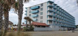 a tall white building with blue balconies on it at Fountain Beach Resort - Daytona Beach in Daytona Beach