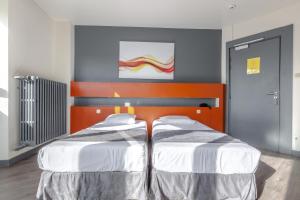 two beds in a bedroom with an orange and blue wall at Hotel Esplanade in Strasbourg