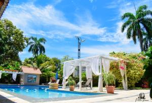 un cenador blanco junto a la piscina en Auberge Villa Cana, en Cabo Haitiano