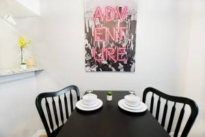 a black table with two chairs and a pink sign at The Alcove Dallas Near Downtown Fun Nightlife in Dallas