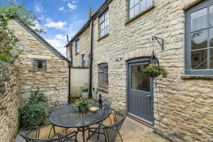 ウッドストックにあるOxfordshire Living - The Bowler Hat Cottage - Woodstockの建物の前にパティオ(テーブル、椅子付)