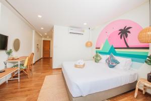 a bedroom with a bed and a table and a desk at Summer Stay Sattahip in Sattahip