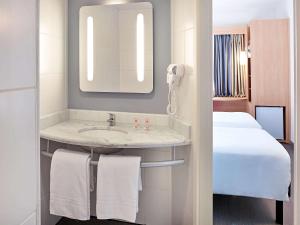 bagno con lavandino, letto e specchio di ibis Londrina Shopping a Londrina