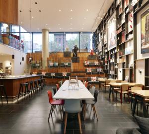 citizenM New York Bowery في نيويورك: غرفة طعام مع طاولات وكراسي ورفوف كتب