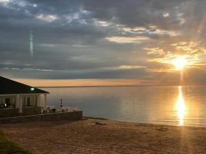 ein Haus am Strand mit Sonnenuntergang über dem Wasser in der Unterkunft Breakers Resort - Lakeside in Saint Ignace