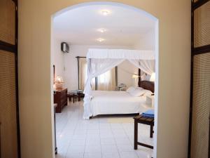 1 dormitorio con 1 cama blanca con dosel en Woburn Residence Club, en Malindi