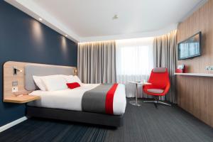 Pokój hotelowy z łóżkiem i czerwonym krzesłem w obiekcie Holiday Inn Express London Luton Airport, an IHG Hotel w Luton