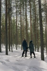 two people walking through the woods in the snow at LakeLodge Kiehinen & Igloos in Rovaniemi