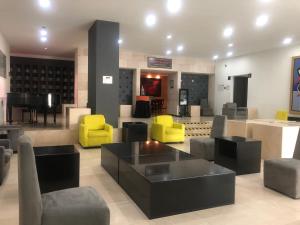 a lobby with yellow and black chairs and a piano at We Hotel Aeropuerto in Mexico City