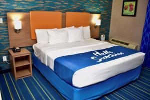 een hotelkamer met een groot bed met een blauwe en witte sprei bij Days Inn by Wyndham Wayne in Wayne