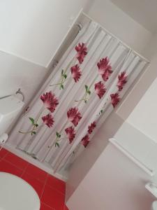 un bagno con finestra con fiori rosa sulla tenda di L'attico b&b a Cirò Marina