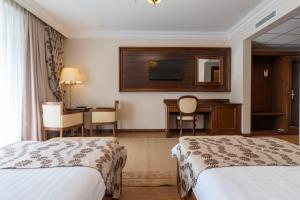 a hotel room with two beds and a desk at Hotel Gabriela in Vişeu de Sus