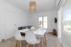 a white dining room with a white table and white chairs at Chalet a 150m de la playa y piscina privada in Cala'n Bosch