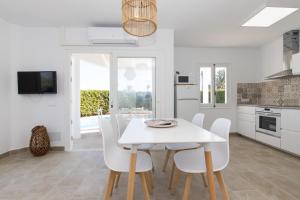 a kitchen and dining room with a white table and chairs at Chalet a 150m de la playa y piscina privada in Cala'n Bosch