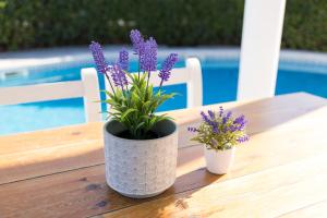 two vases with purple flowers sitting on a wooden table at Chalet a 150m de la playa y piscina privada in Cala'n Bosch